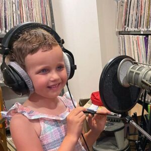 A young girl is excited to begin recording her original content for the radio.